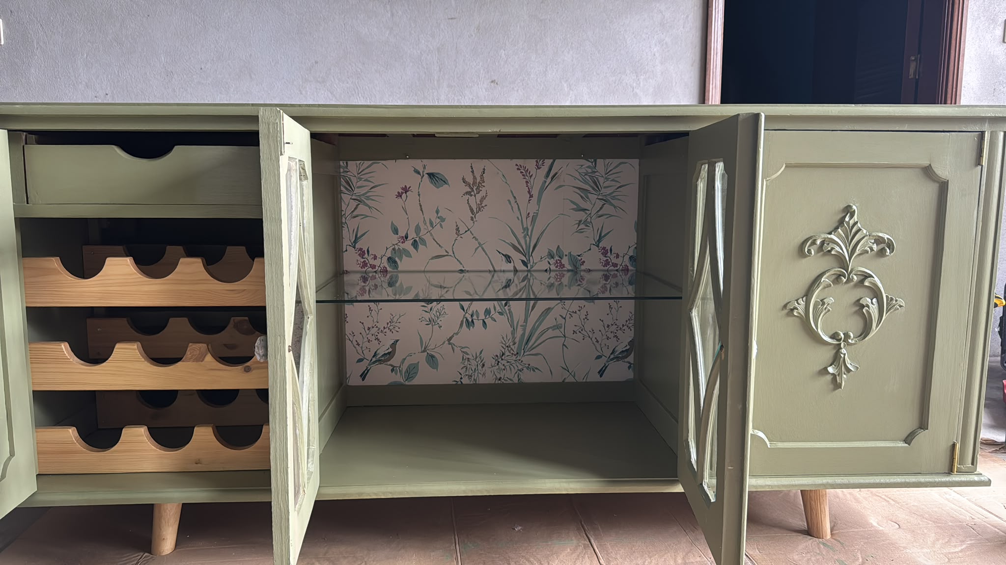 Por dentro: papel de parede, prateleira de vidro e uma garrafeira construída de raiz.